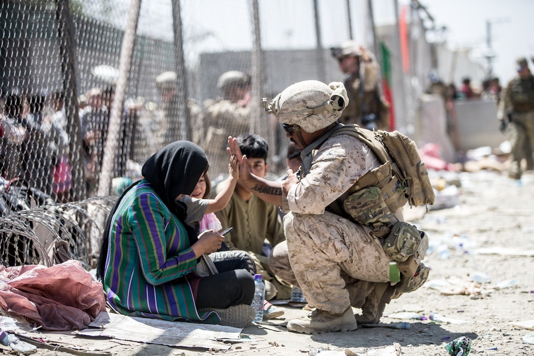 A Marine with Special Purpose Marine Air-Ground Task Force-Crisis Response-Central Command gives a high five to a child at HKIA, Augustus 26, 2021.